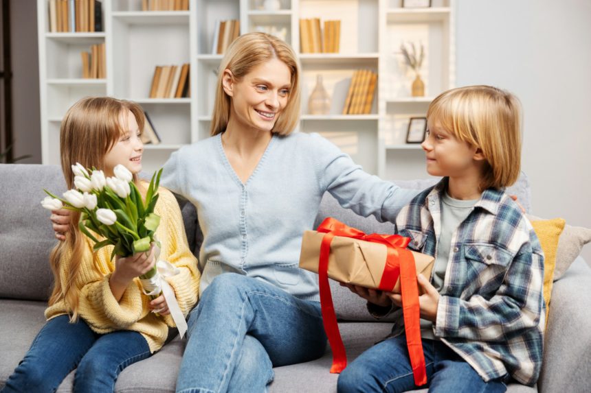 Happy family celebrating Mother's Day at home. Kids are gifting their mom