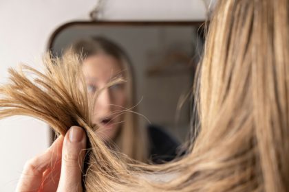 young woman in front of mirror sad upset with hair loss damage problem